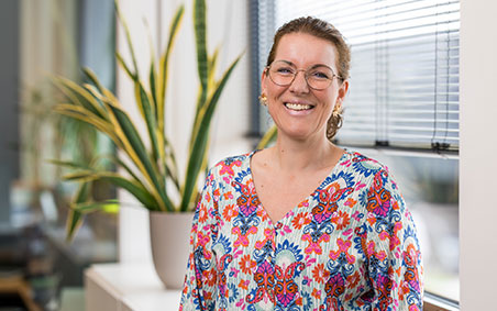  A smiling Eveline in a colorful blouse and glasses